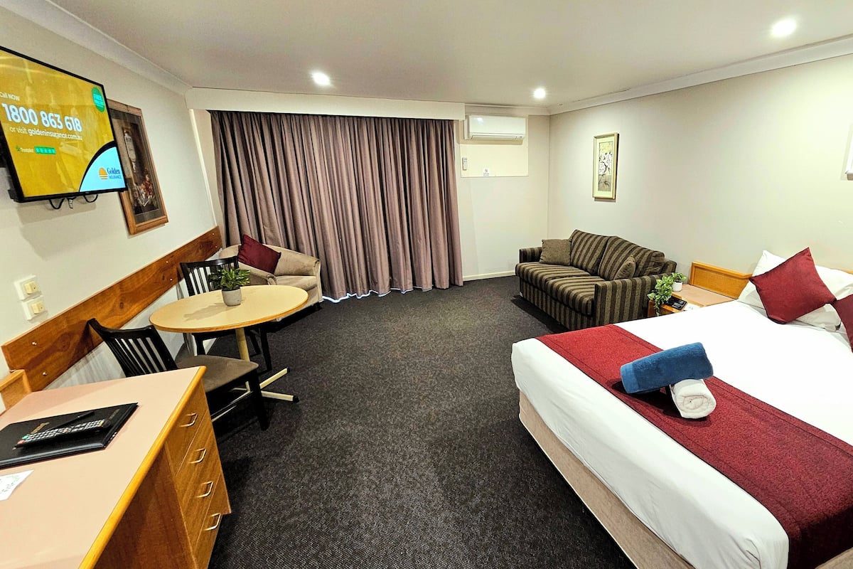 A hotel room with a bed, a sofa, a desk, and a chair.
