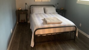 A neatly arranged bedroom with a bed, two bedside tables, a wall-mounted artwork, and a window.