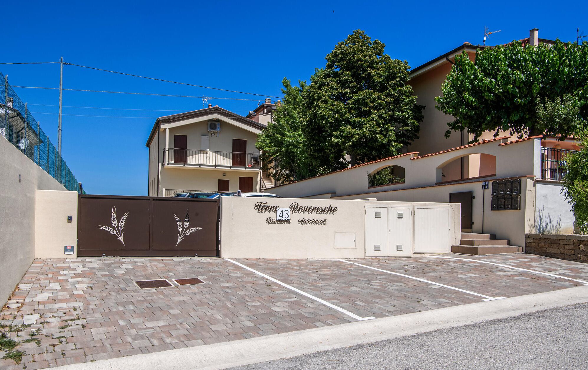 A residential building with a gated entrance, a parking area, and a sign indicating 'Tenne 43 Rouenese Residences Apartments'.