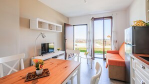 A modern kitchen with a refrigerator, a dining table with chairs, a TV, and a view of the outdoors. - Pet friendly apartment in Terre Roveresche (Terre Roveresche)