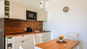 A compact kitchen with white cabinets, a microwave, a coffee maker, and a wooden table with chairs. - Pet friendly apartment in Terre Roveresche (Terre Roveresche)