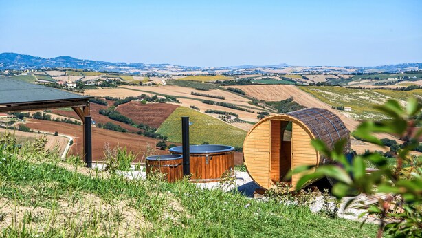 A rustic wooden cabin with a curved roof, surrounded by lush greenery and a panoramic view of rolling hills and fields. - Pet friendly apartment in Terre Roveresche (Terre Roveresche)