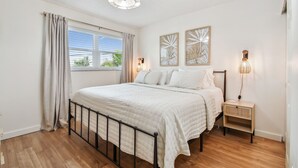 A bedroom with a bed, a nightstand, a lamp, and artwork on the wall. - 2024 updated condo with water views! (Treasure Island)