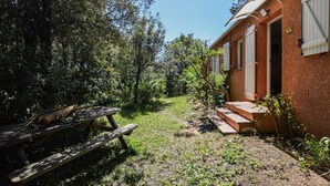Uma área externa rústica com uma mesa de piquenique e um edifício de fachada vermelha.