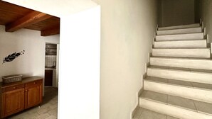 A staircase with a wooden beam ceiling, a white wall with a decorative leaf decal, and a kitchen area in the background. - SE080 - Senigallia, comfortable four-room apartment in the historic center (Senigallia)