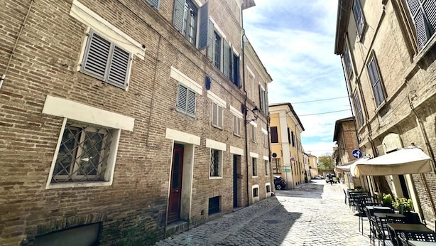 A narrow cobblestone street lined with traditional brick buildings, some with shutters, and outdoor seating at a café. - SE080 - Senigallia, comfortable four-room apartment in the historic center (Senigallia)