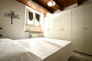 Ein Schlafzimmer mit Bett, Kleiderschrank, Heizkörper und einem fenster mit Vorhängen.