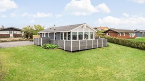 A modern house with a large glass conservatory, surrounded by a well-maintained lawn and a wooden fence. - Nice home in Lemvig with WiFi (Lemvig)