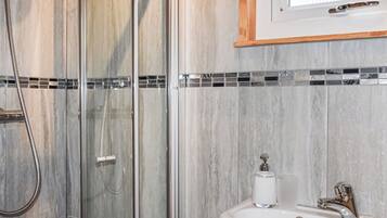 A bathroom with a glass shower enclosure, a sink with a chrome faucet, and a mirror above the sink.