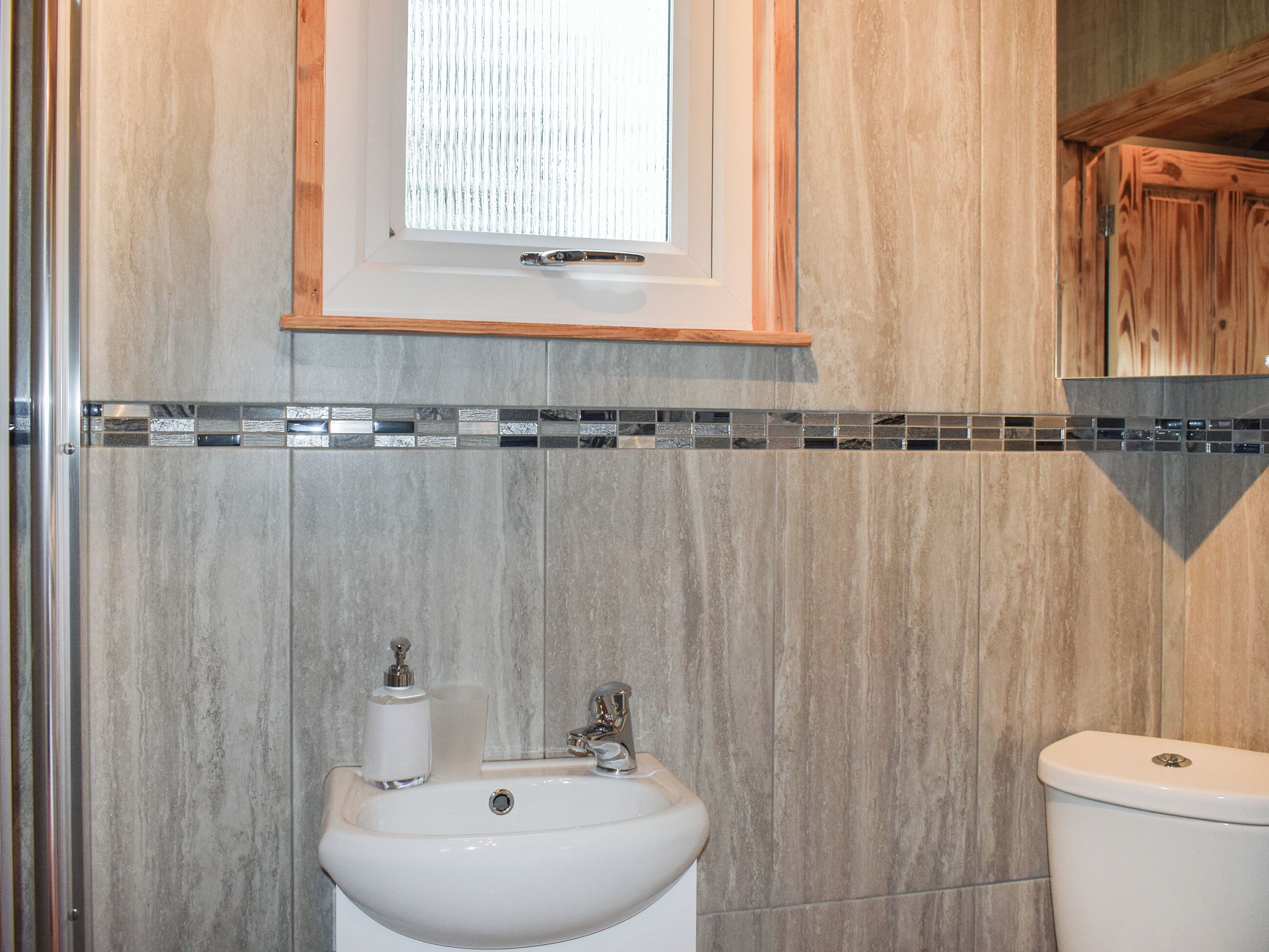 Une salle de bain équipée d’un lavabo, de toilettes et d’une fenêtre située au-dessus du lavabo.