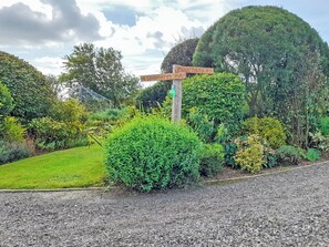 Ein Garten mit einem hölzernen Wegweiser, der zu 'Moorhens' und der 'Shepherd's Hut' weist.