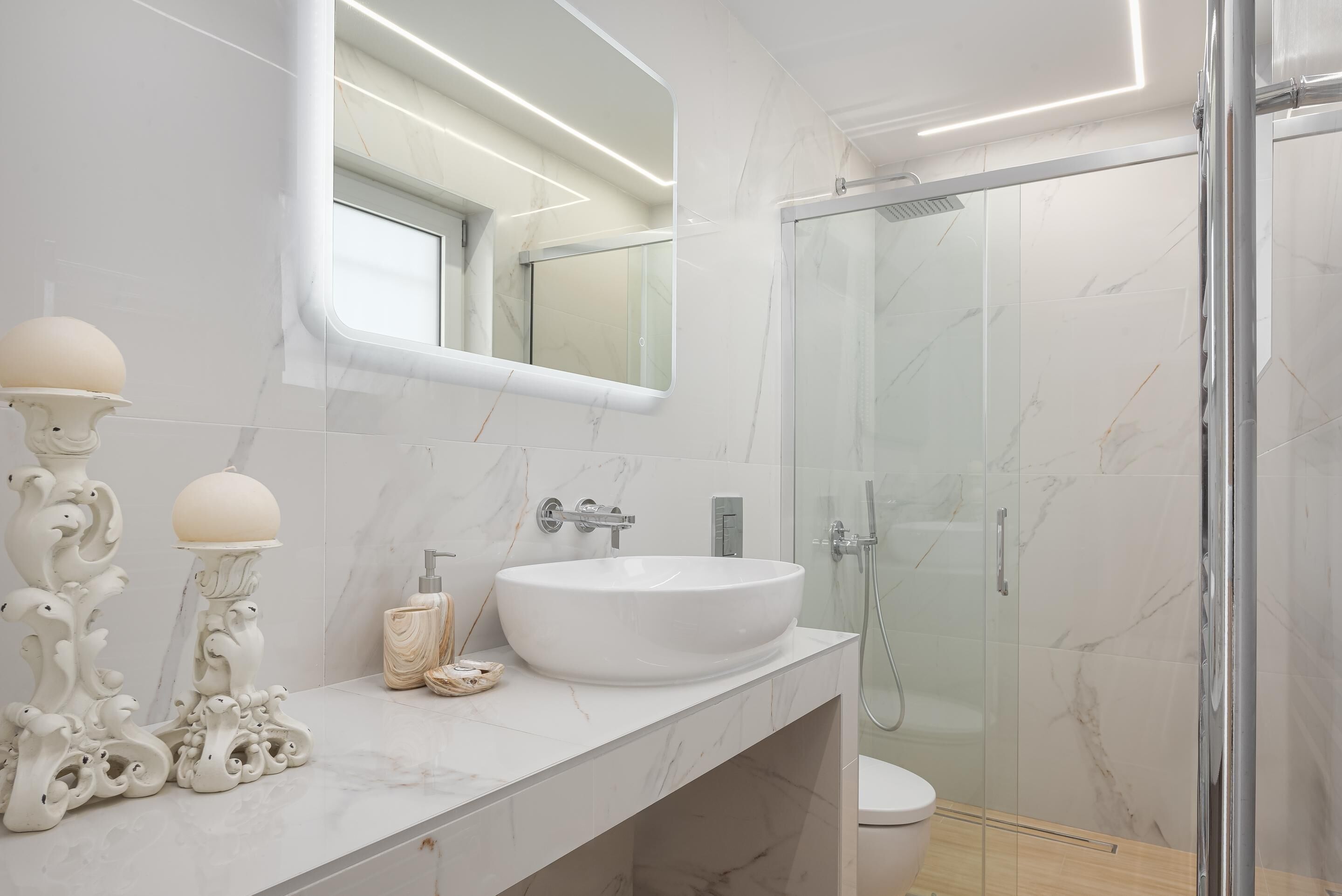 A modern bathroom with a large white sink, a mirror, and a glass shower enclosure.