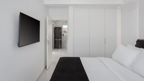 Un dormitorio moderno con una cama grande, un televisor de pantalla plana montado en la pared y un vestidor.