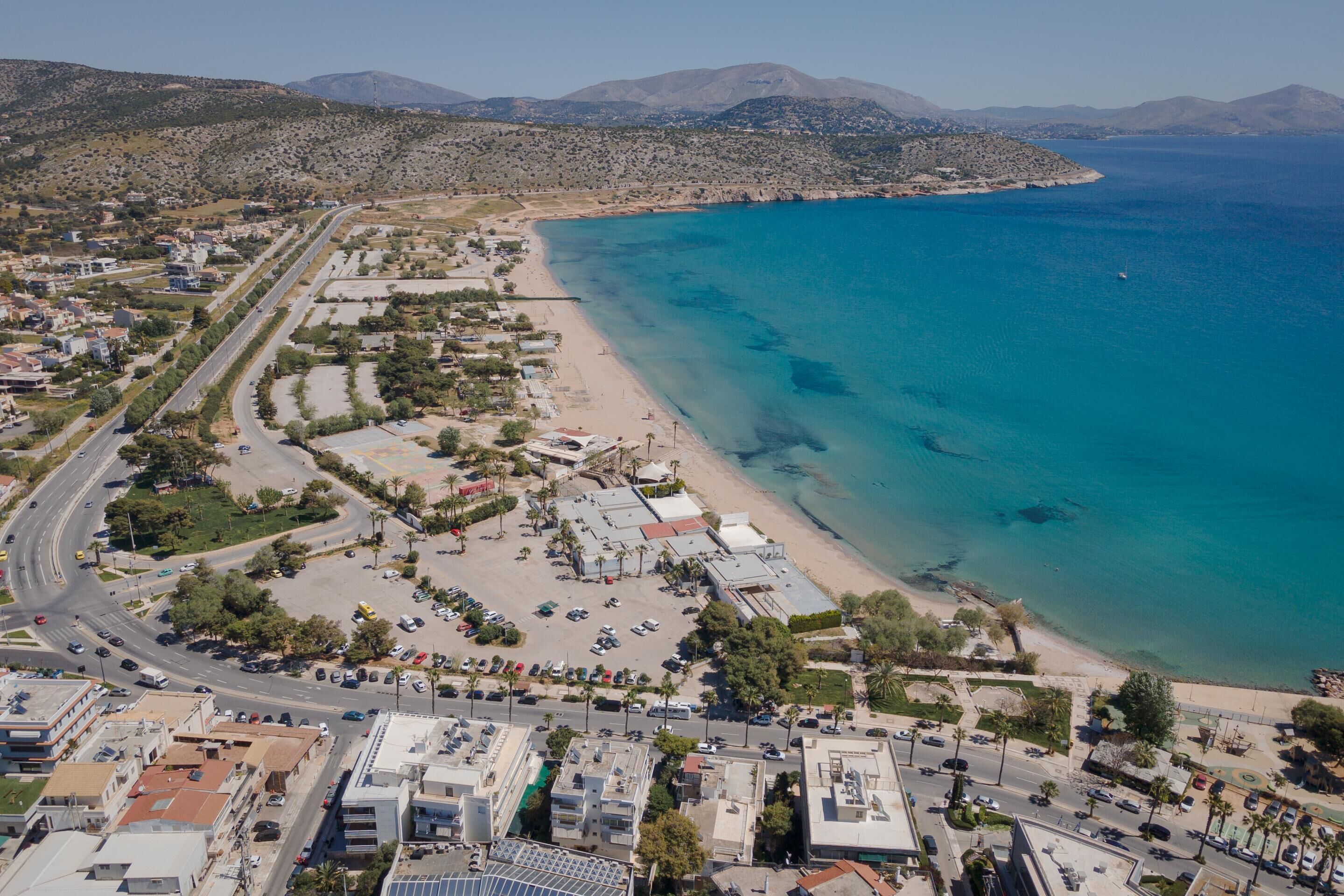 An aerial view of a coastal town with a beach, roads, and buildings.