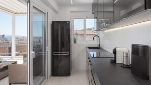 Una cocina moderna con un refrigerador negro, un lavamanos y un cubo de basura.