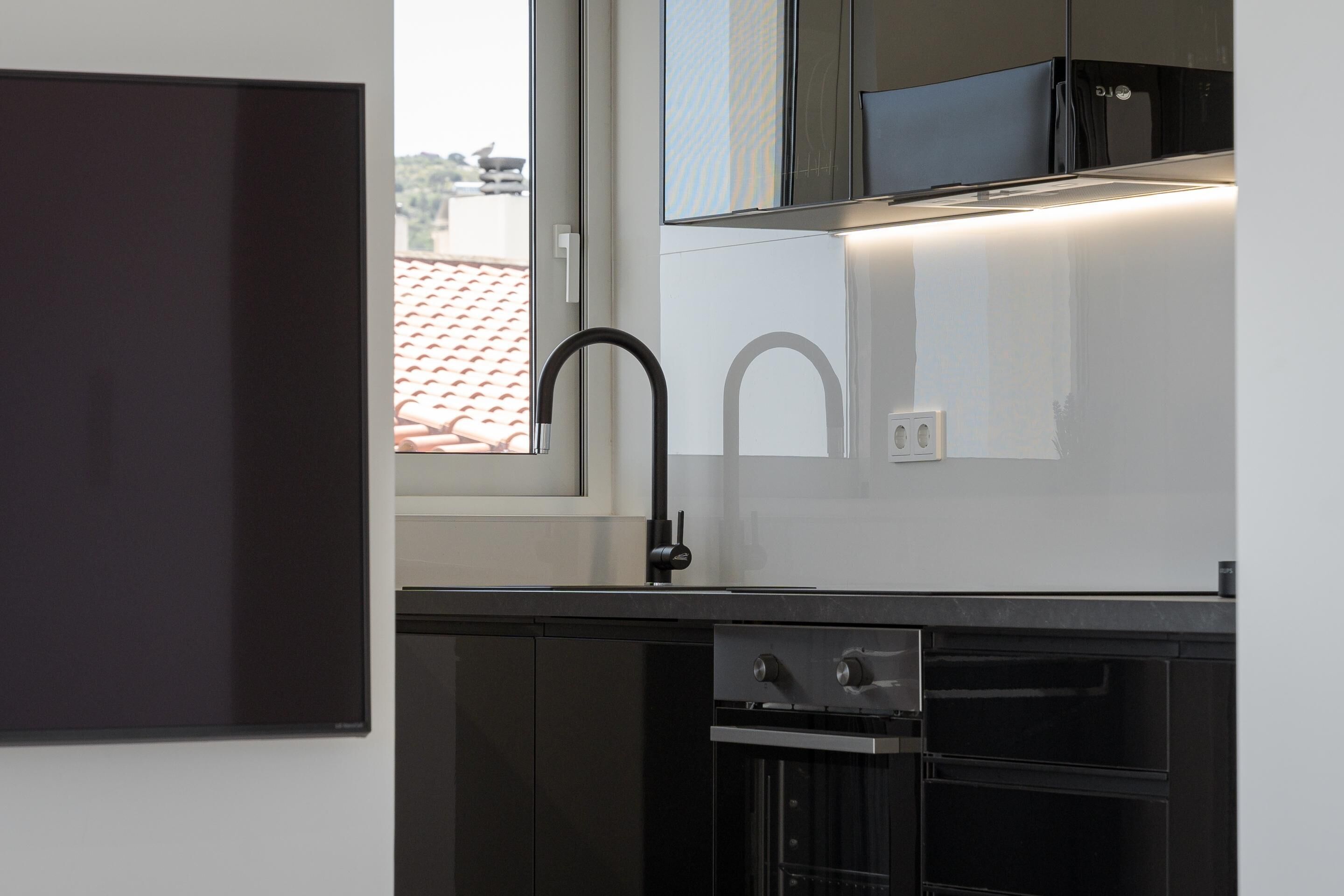 Une cuisine moderne avec des meubles de couleur noire, un évier en acier inoxydable et un four à micro-ondes.