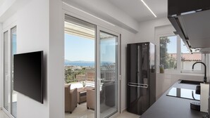 Una cocina moderna con un gran ventanal, un televisor de pantalla plana y un balcón con mobiliario exterior.