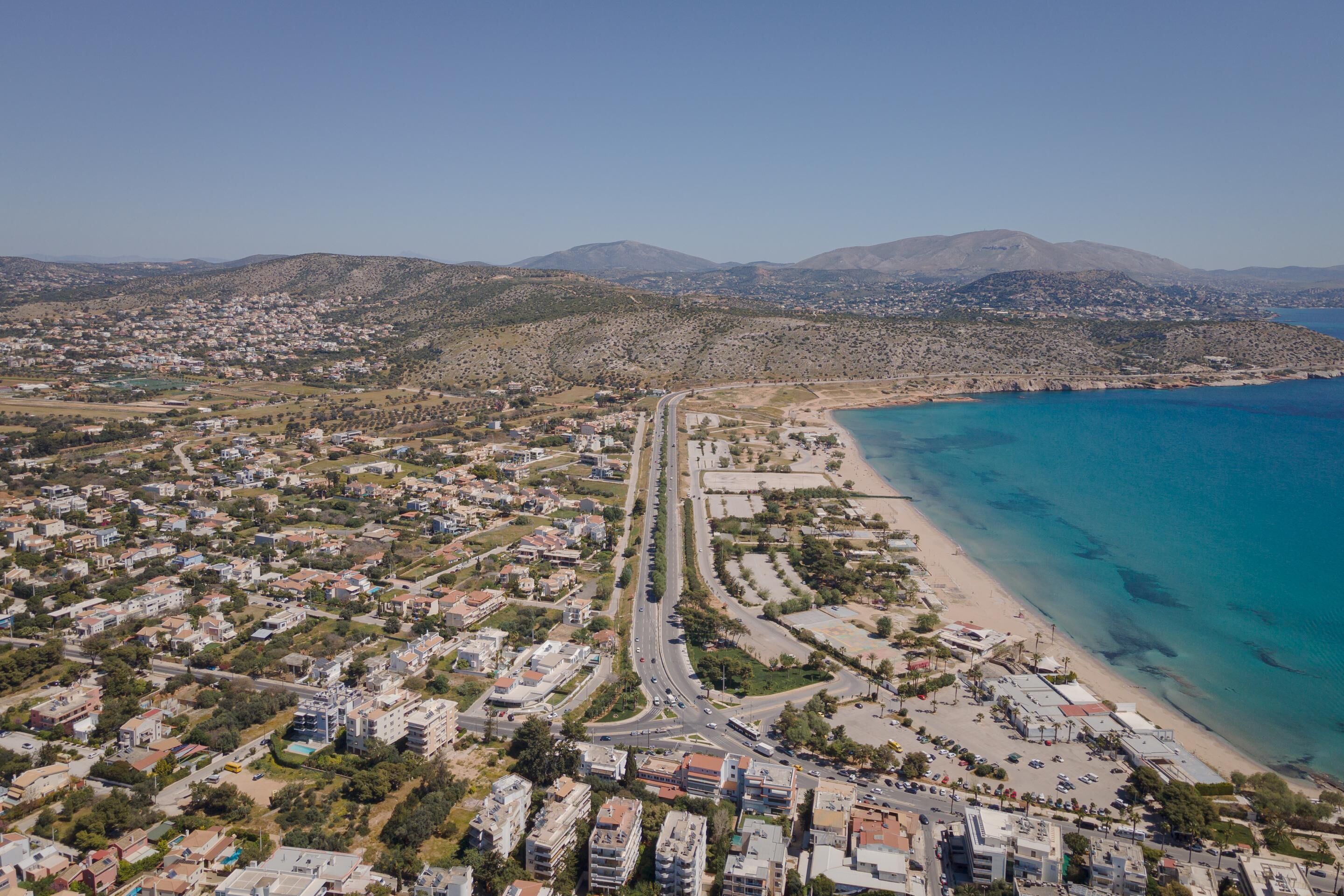 Une vue aérienne d’une ville côtière, avec une plage, des zones résidentielles et une route menant à la plage.