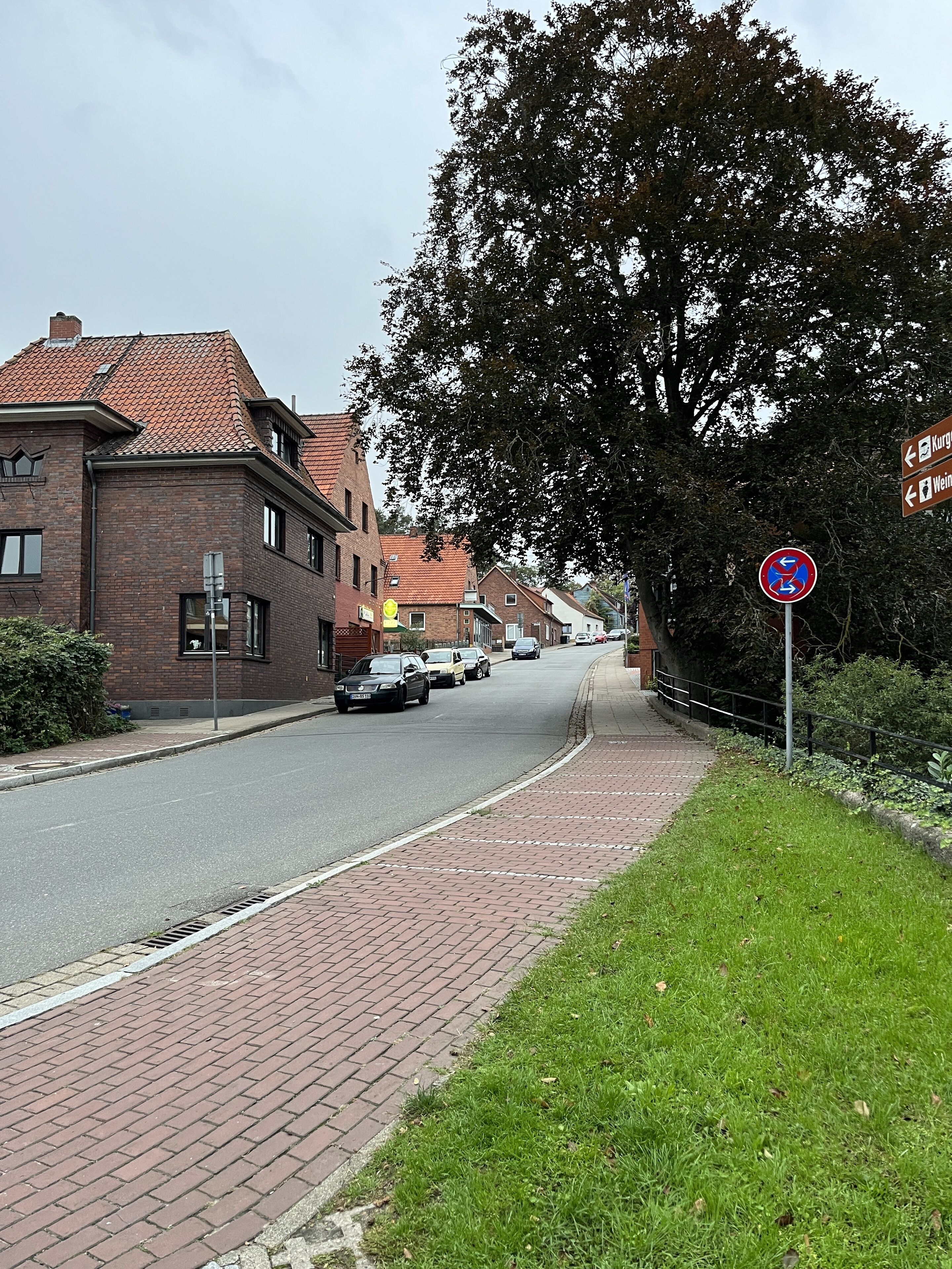 A street with brick buildings, a no parking sign, and a sidewalk.