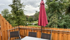 An outdoor patio with a table and chairs, a wooden fence, and a view of a residential area. - Zentral Gelegene Ferienwohnung Am Langenberg, Hitzacker (Hitzacker (Elbe))