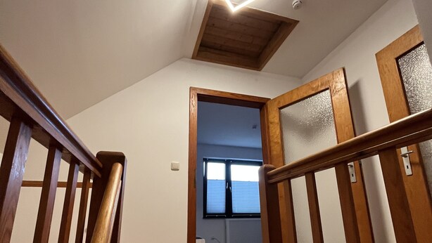 A wooden staircase with a modern light fixture, leading to a room with a view through a window. - Zentral Gelegene Ferienwohnung Am Langenberg, Hitzacker (Hitzacker (Elbe))