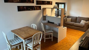 A compact living space with a dining area, a kitchenette, a sofa, and artwork on the walls. - Zentral Gelegene Ferienwohnung Am Langenberg, Hitzacker (Hitzacker (Elbe))