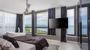 A modern bedroom with a large bed, a bathtub, and a TV. - Stunning home in Opatija with sauna (Opatija)