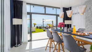 A modern dining area with a view of the sea, featuring a table with chairs, a vase of flowers, and a breakfast tray. - Stunning home in Opatija with sauna (Opatija)