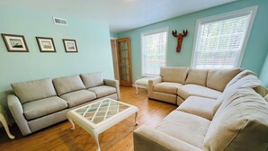 A living room with two beige sofas, a glass coffee table, and a wooden door. - Acadia Retreat:18 Miles to Acadia NP!Secluded, Pet Friendly, Spacious. (Ellsworth)