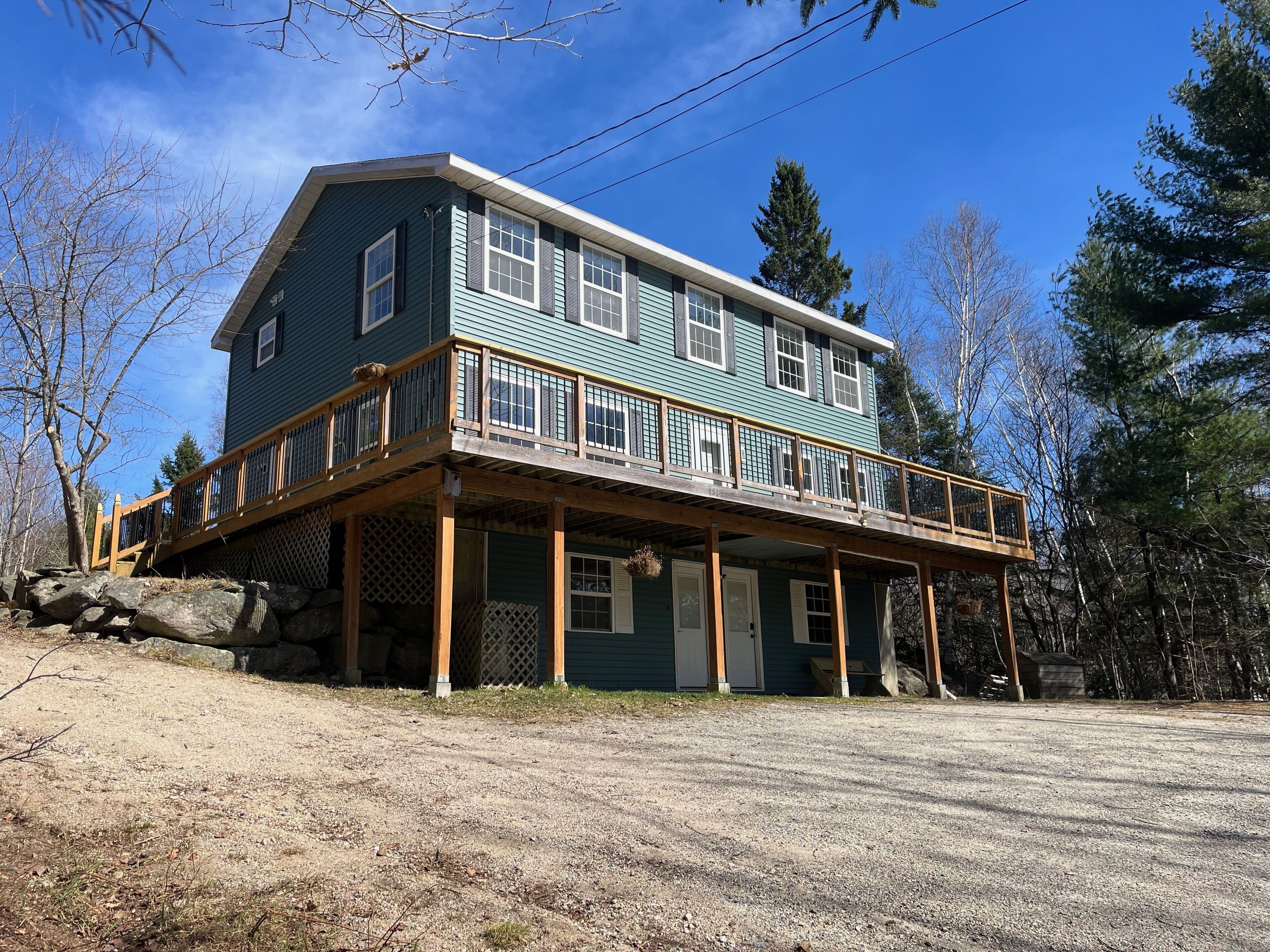 A two-story house with a wooden deck and a covered porch.