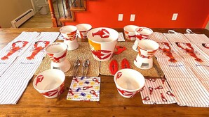 A dining table with multiple lobster-themed cups and plates, arranged on a wooden table with a red wall in the background. - Acadia Retreat:18 Miles to Acadia NP!Secluded, Pet Friendly, Spacious. (Ellsworth)