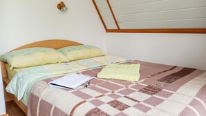 Un dormitorio con cabecera de madera, cama con manta estampada, una toalla amarilla y una libreta sobre la cama.