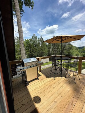 A wooden deck with a barbecue grill, outdoor table, and chairs. - New Modern A-Frame Near Mammoth Cave National Park with Nolin Lake Views! (Cub Run)