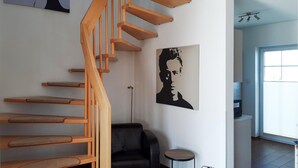 Eine Treppe mit Holzstufen und ein schwarzer Ledersessel in einem Raum mit einem großen Fenster und Kunstwerken an der Wand.