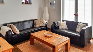 Ein Wohnzimmer mit zwei schwarzen Ledersofas, einem Holztisch und einem gewebten Korb.