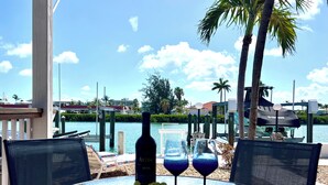 A glass table with a bottle of wine, two wine glasses, and a plate of grapes. - DISCOUNT! Beautiful Home, Dock, Cabana Club Membership, Pool, Beach! (Key Colony Beach)