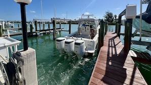 A boat docked at a marina with a wooden pier and a clear blue sky. - DISCOUNT! Beautiful Home, Dock, Cabana Club Membership, Pool, Beach! (Key Colony Beach)