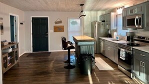 Une cuisine moderne avec un plancher en bois, des appareils électroménagers en acier inoxydable et un coin bar.