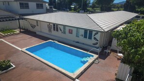 A building with a swimming pool, a covered patio, and a sign indicating pool rules.