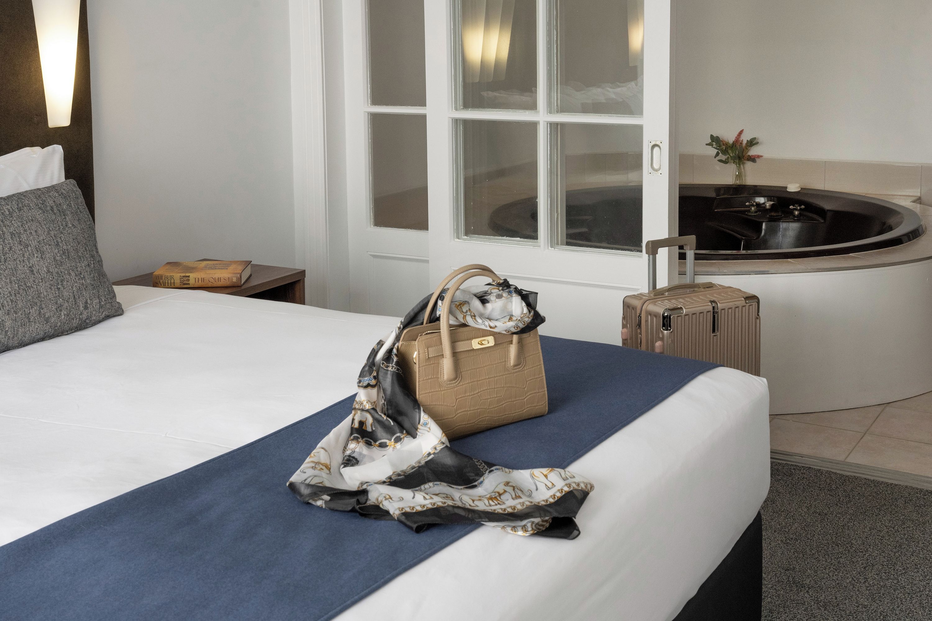 A hotel room with a bed, a bathroom with a bathtub, and a window.