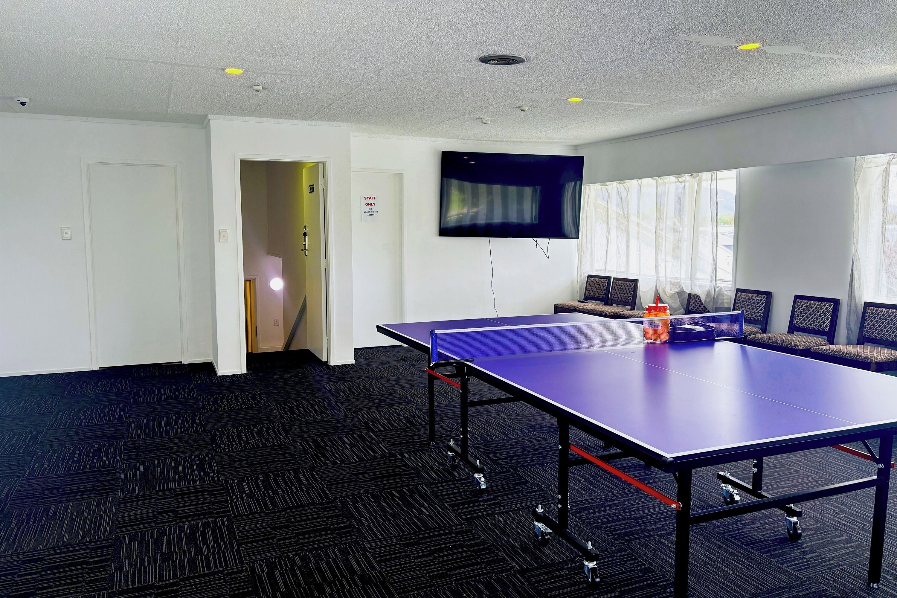 Una habitación con mesa de ping pong, televisión, sofá y puerta.
