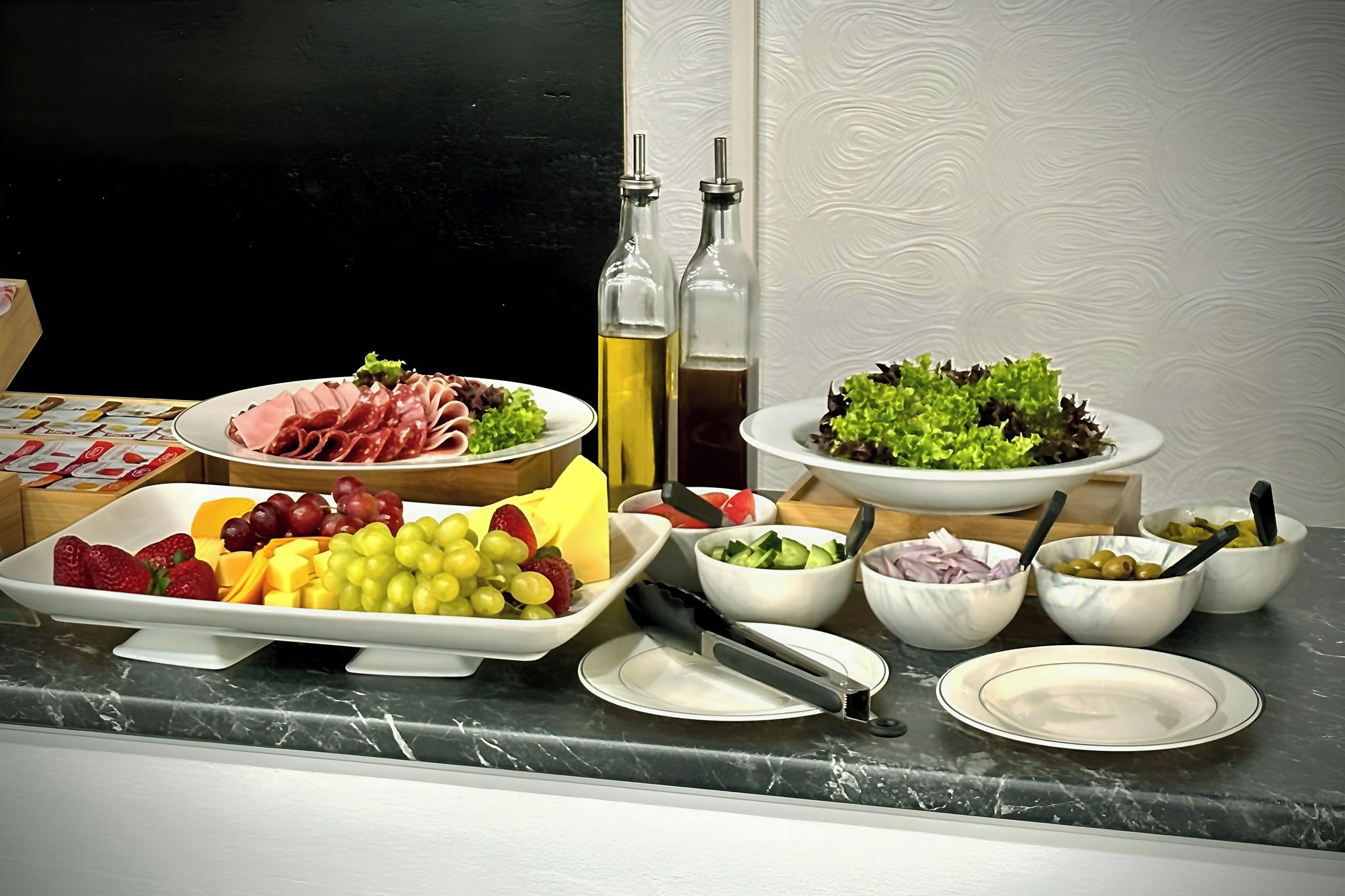A buffet table with various food items including meats, cheeses, fruits, and vegetables.
