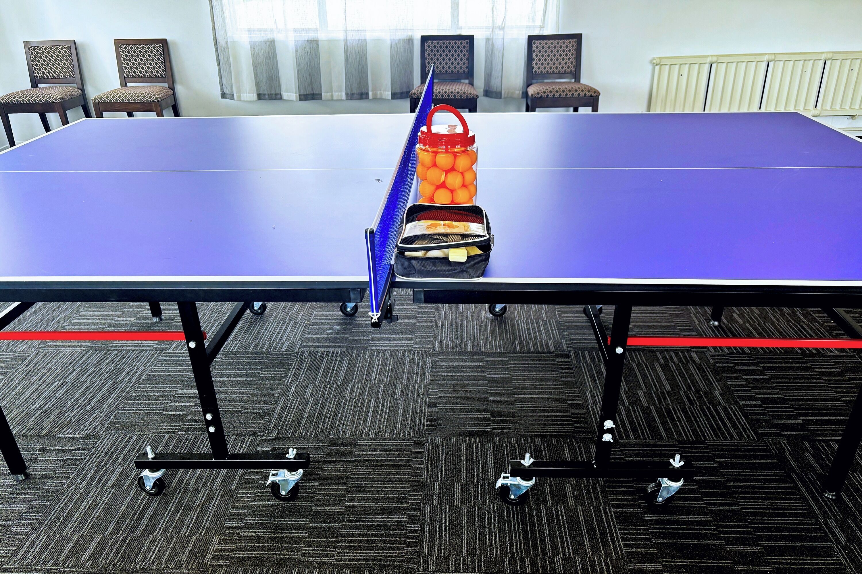 Uma sala de conferências com uma mesa, cadeiras e uma mesa de pingue-pongue.