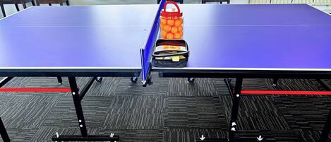 A conference room with a table, chairs, and a table tennis table.