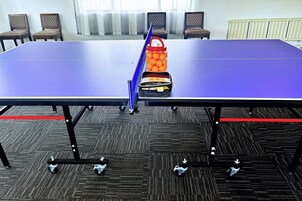 Uma sala de conferências com uma mesa, cadeiras e uma mesa de pingue-pongue.