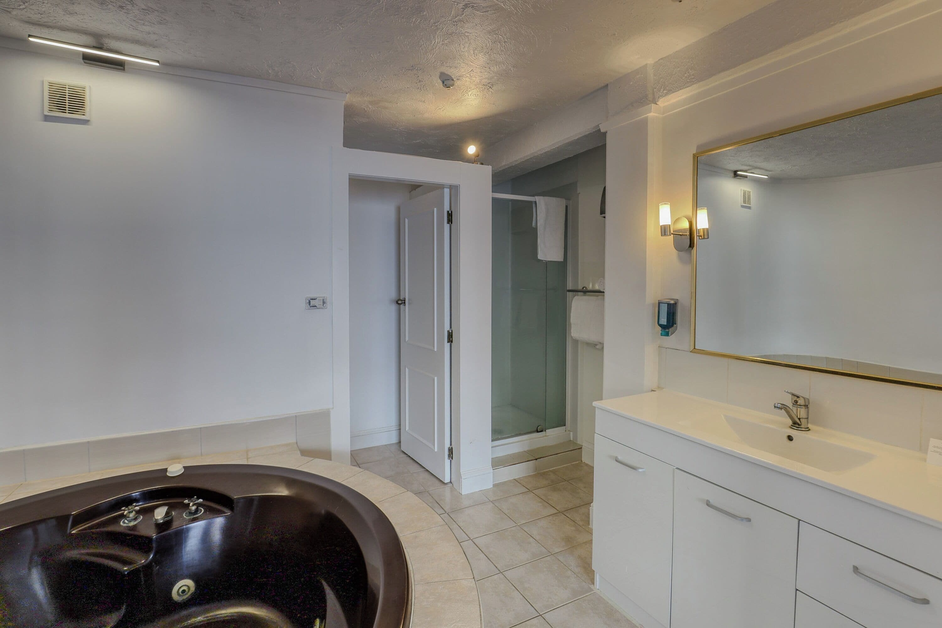 Un baño moderno con bañera, un espejo grande y zona de ducha.