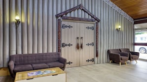 A room with a large wooden door, a brown sofa, two armchairs, and a coffee table.