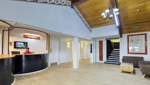 A reception area with a reception desk, a television, a staircase, and a framed informational poster on the wall.