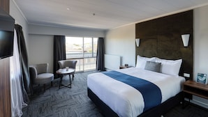 A hotel room with a large bed, a desk, a chair, and a TV.