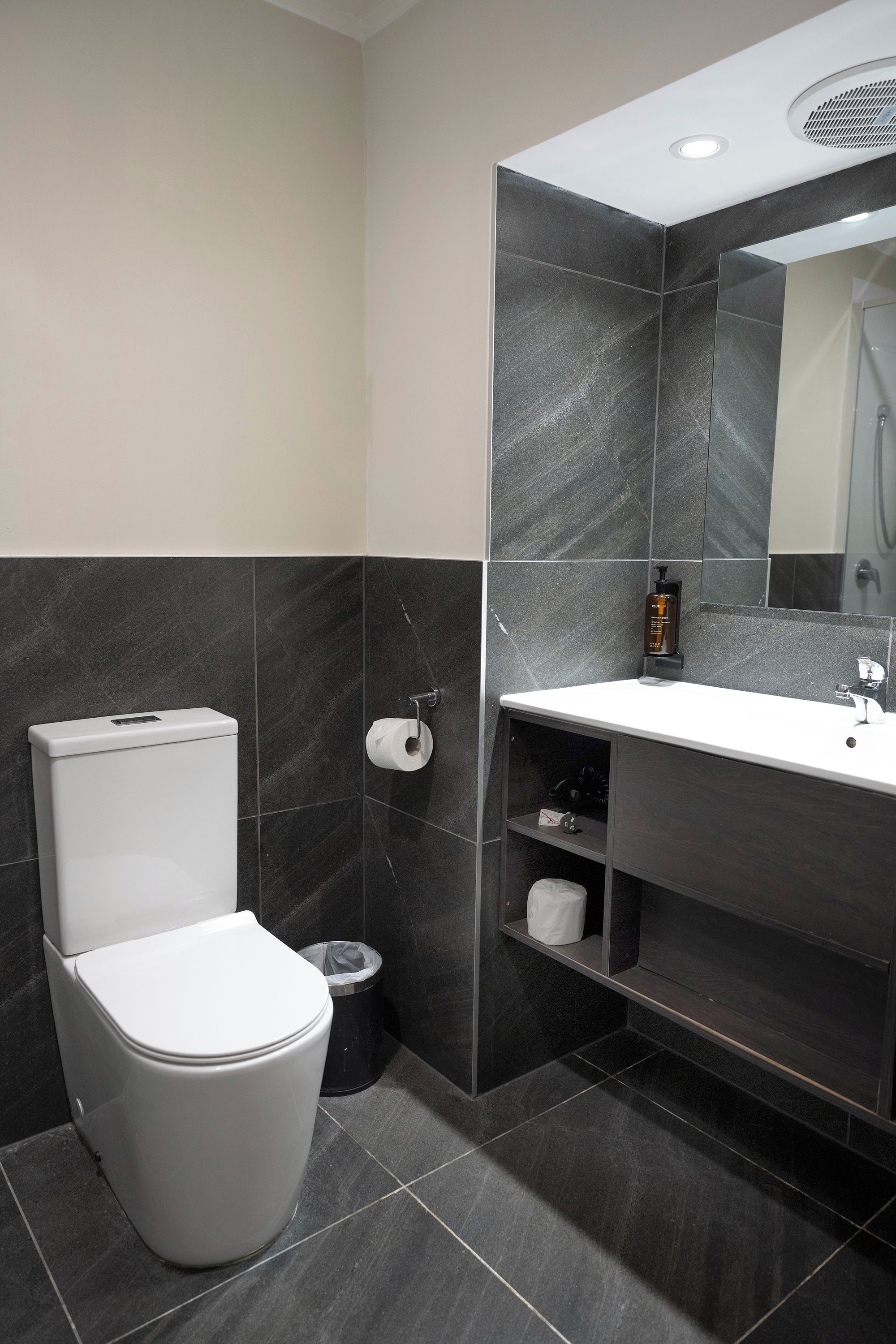 A modern bathroom with a toilet, a sink, and a mirror.